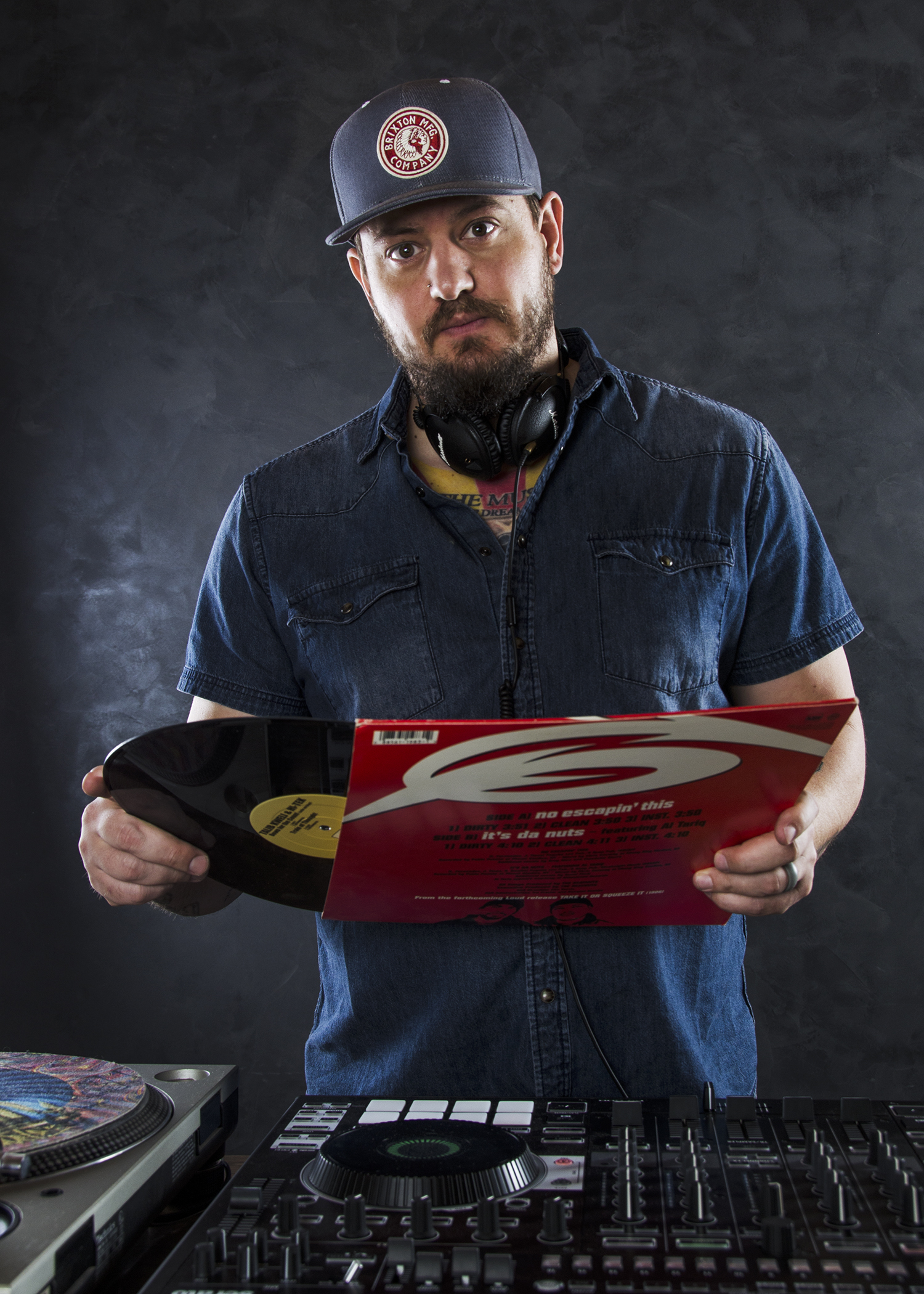 Bear Cole holding a vinyl record behind his DJ equipment